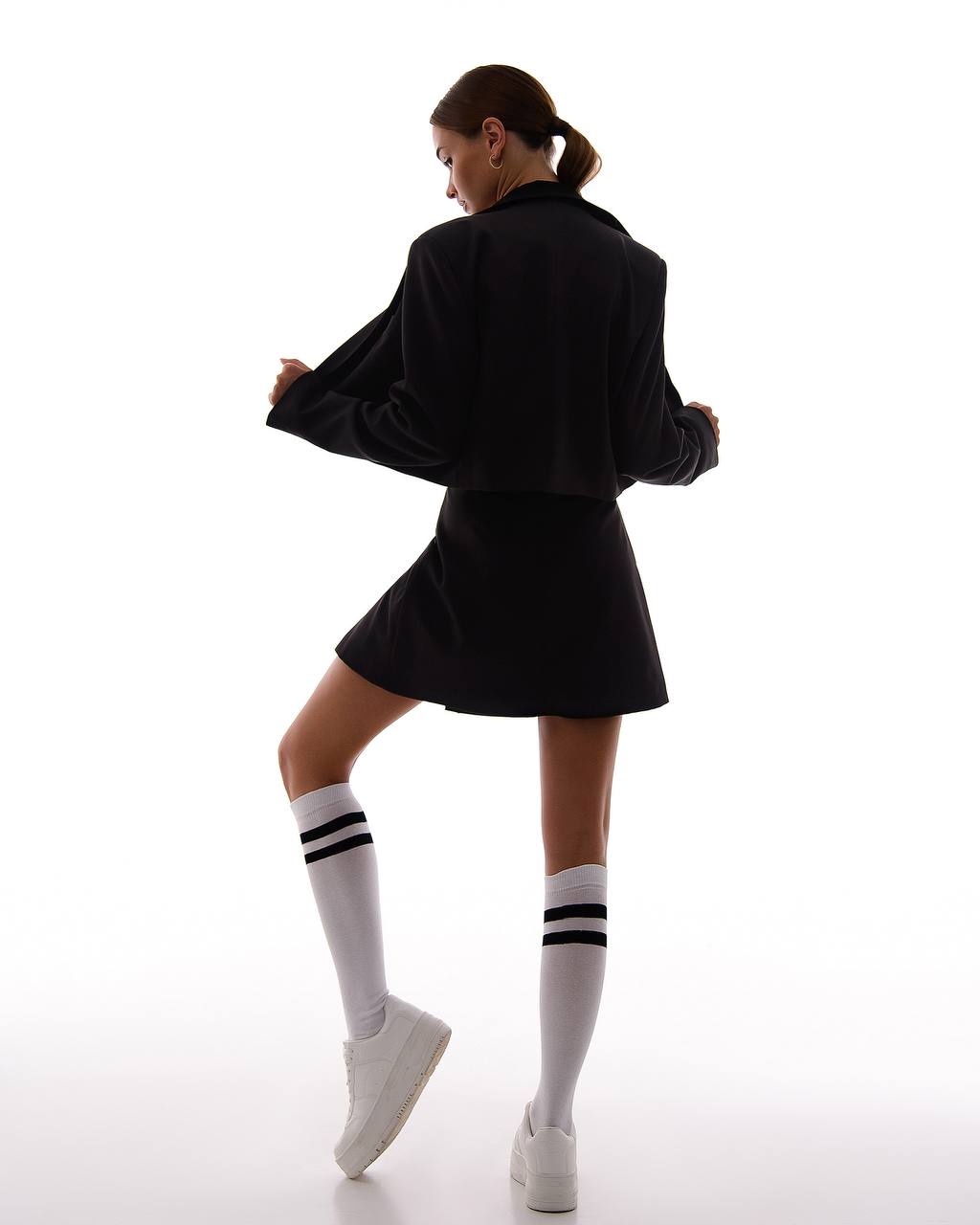 Person wearing a black outfit with white socks on a white background