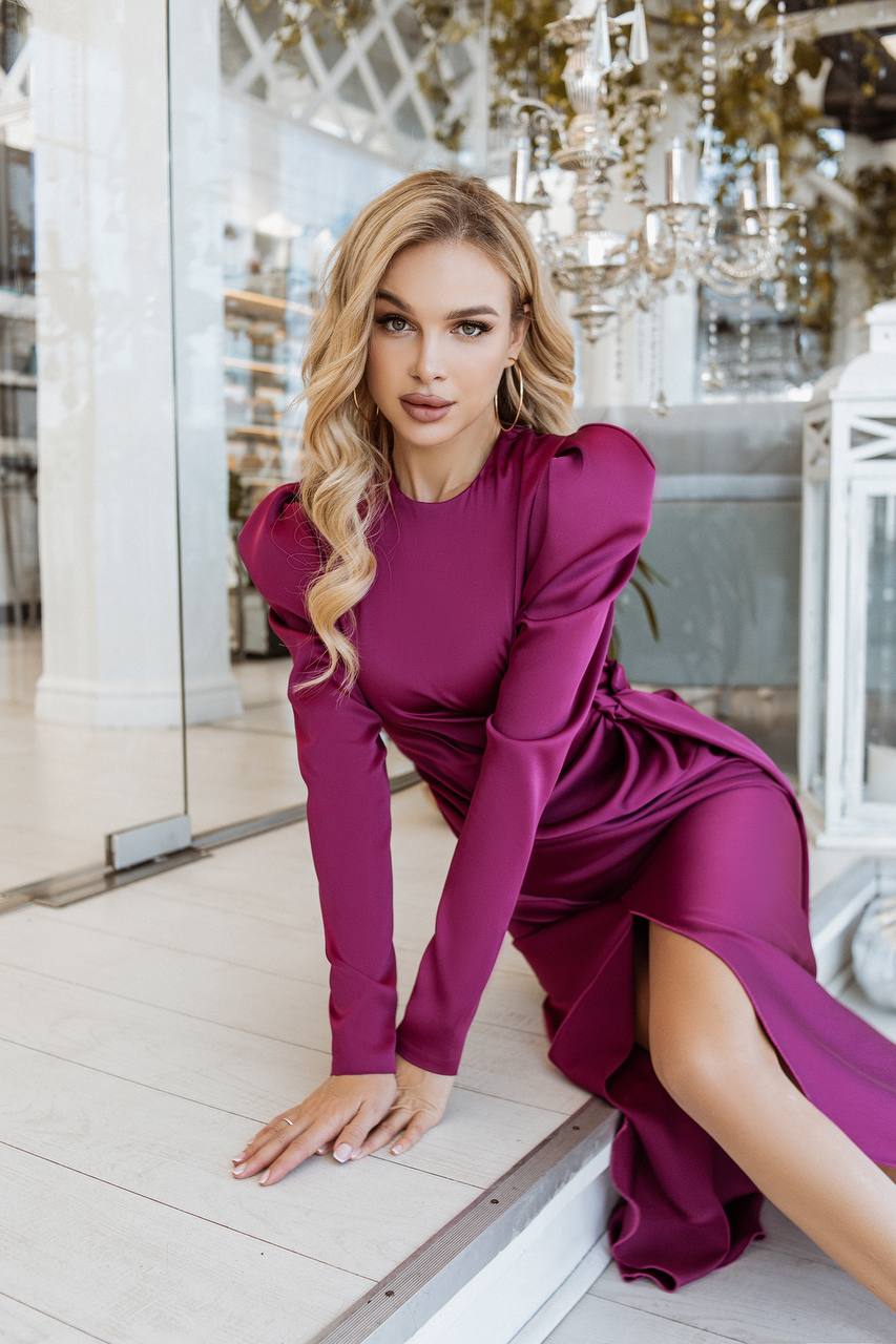 Woman in a magenta dress posing indoors with decorative elements in the background