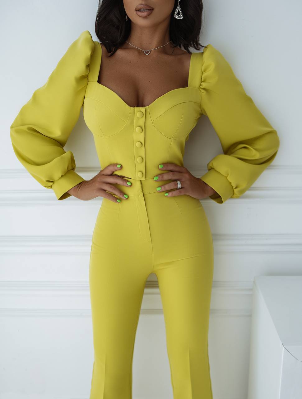 Woman wearing a yellow jumpsuit against a white background