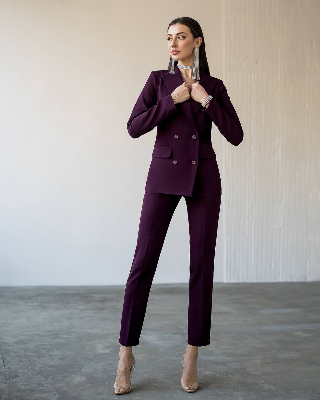 Woman wearing a purple suit standing against a plain background