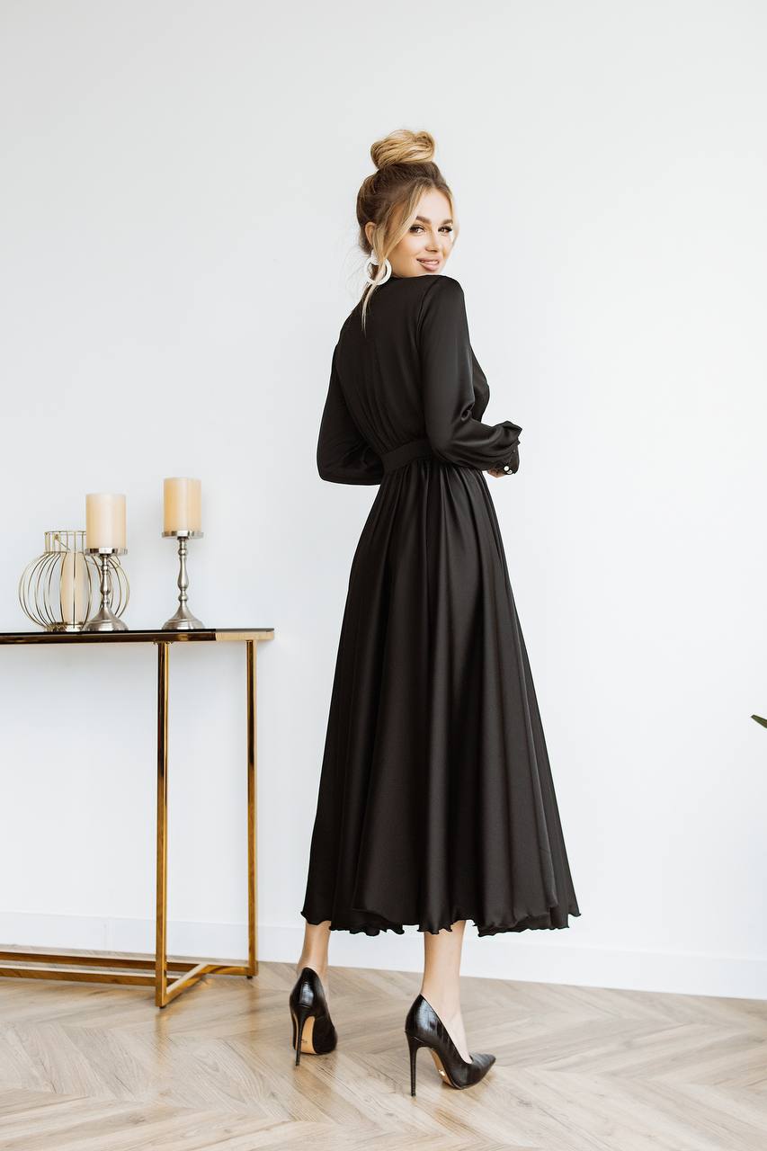 Woman in a black dress standing in a room with a table and candles.