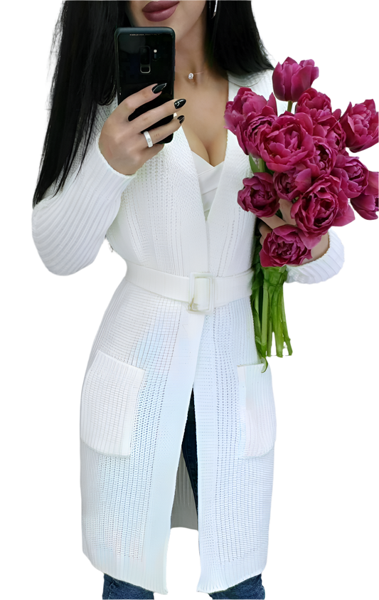 Person wearing a white cardigan holding pink flowers and a phone.