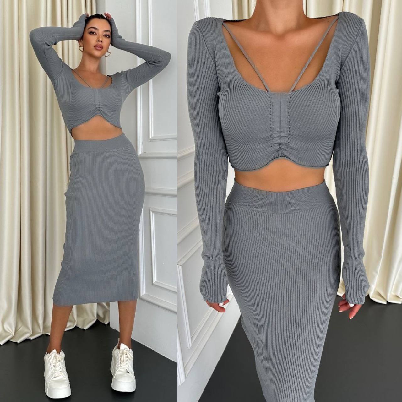 Woman wearing a gray ribbed two-piece outfit with long sleeves and a skirt, standing against a white wall.