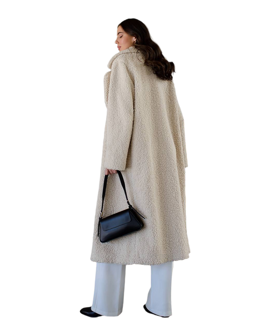 Woman wearing a long beige coat holding a black handbag on a white background