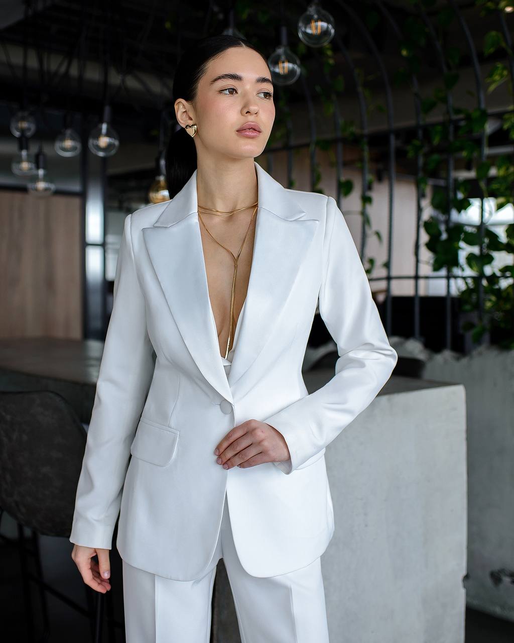 Woman wearing a white suit with a blurred indoor background