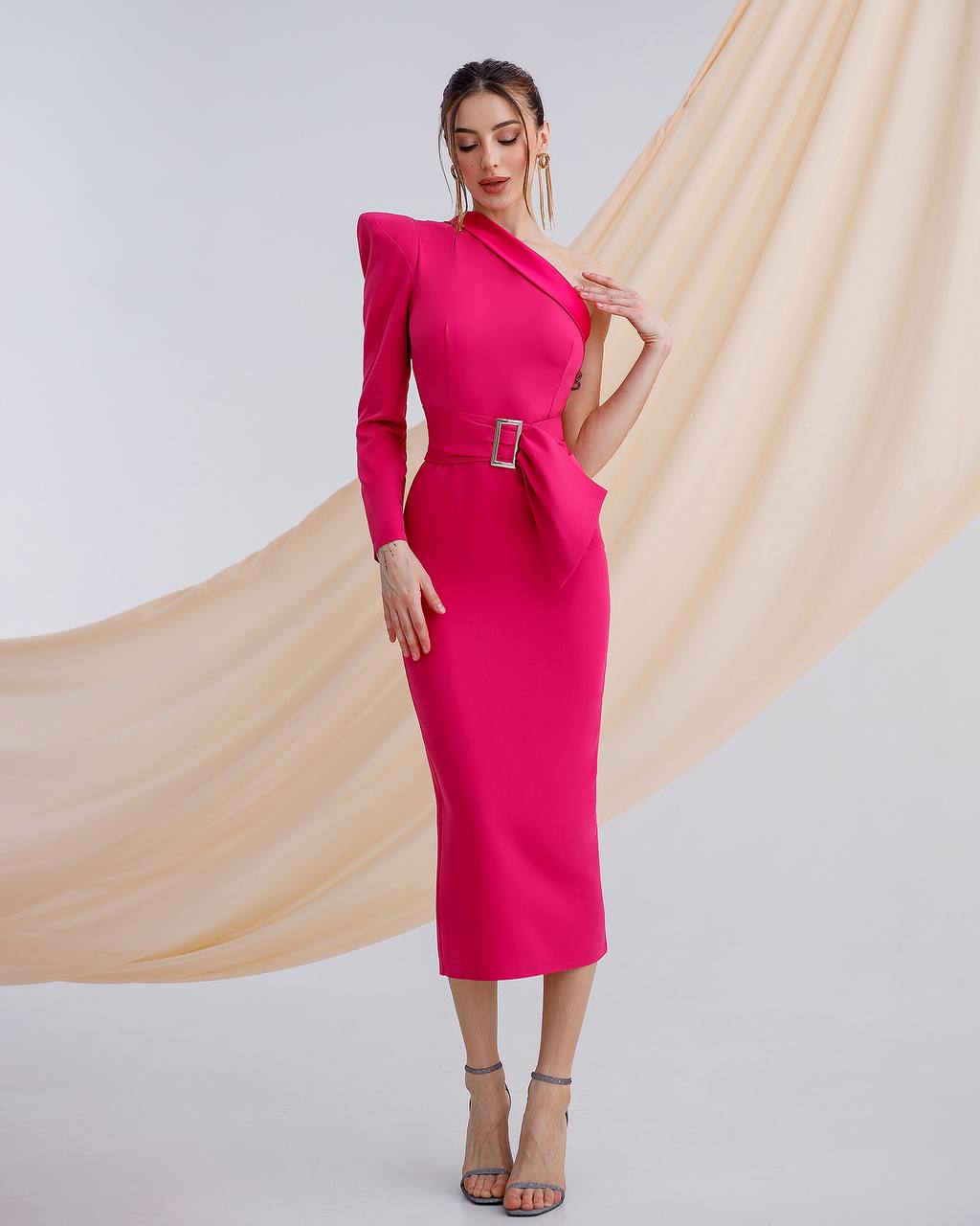 Woman wearing a bright pink dress with a belt, standing against a plain background