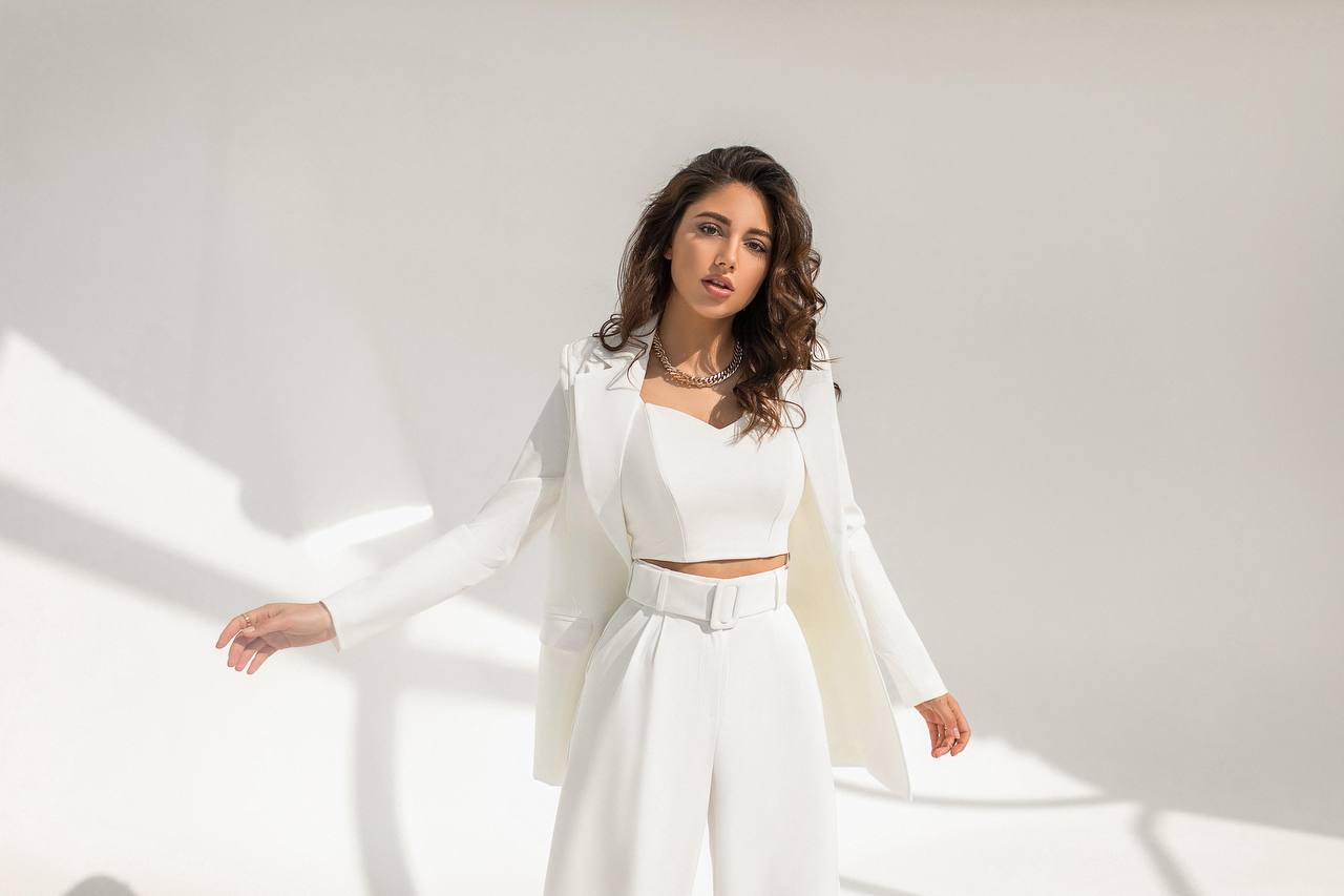 Woman in a white outfit standing against a light background