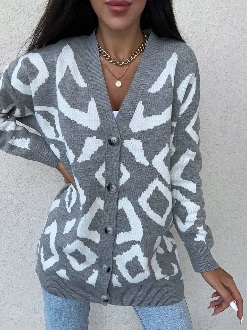 Person wearing a gray cardigan with white geometric pattern against a plain background