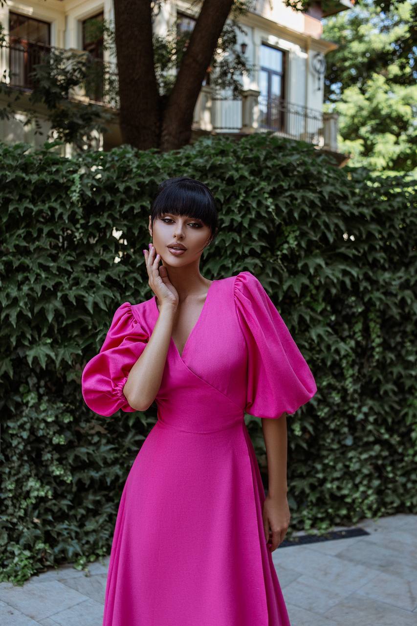 Woman in a bright pink dress standing in front of greenery