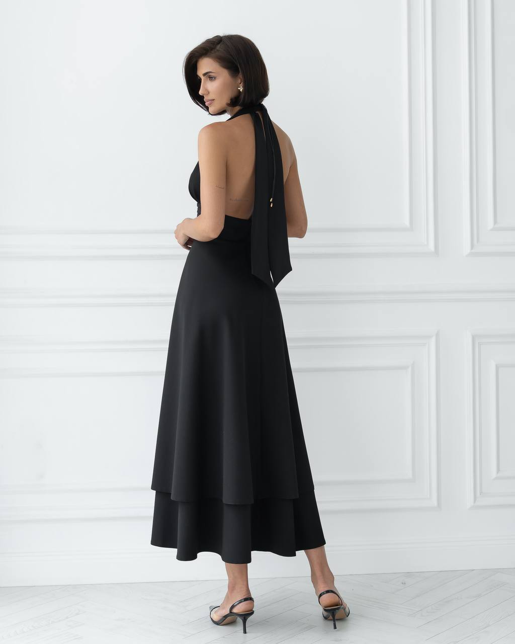 Woman wearing a black dress with a white wall background
