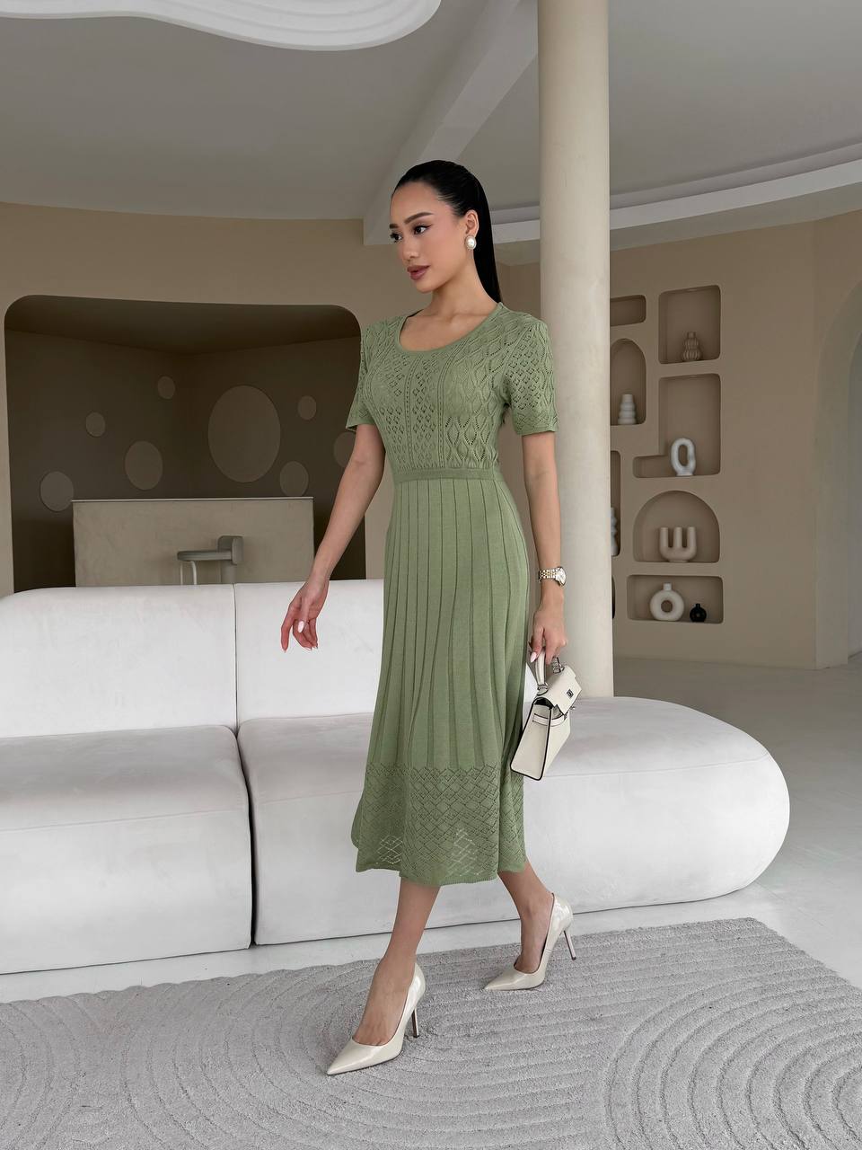 Woman in a green dress standing in a modern interior setting