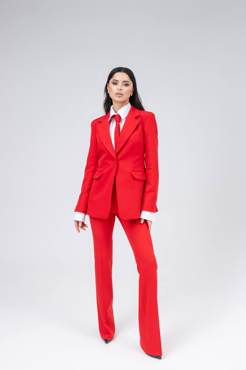 Person wearing a red suit with a white shirt and tie on a light gray background