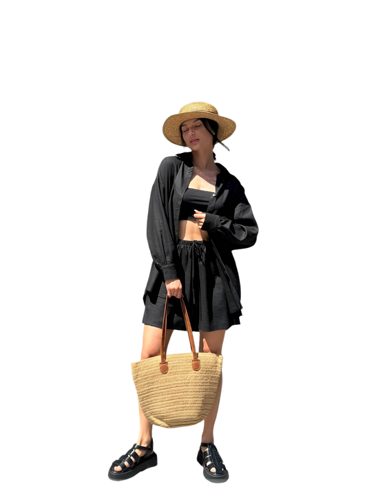 Woman in black outfit with straw hat and bag on a white background