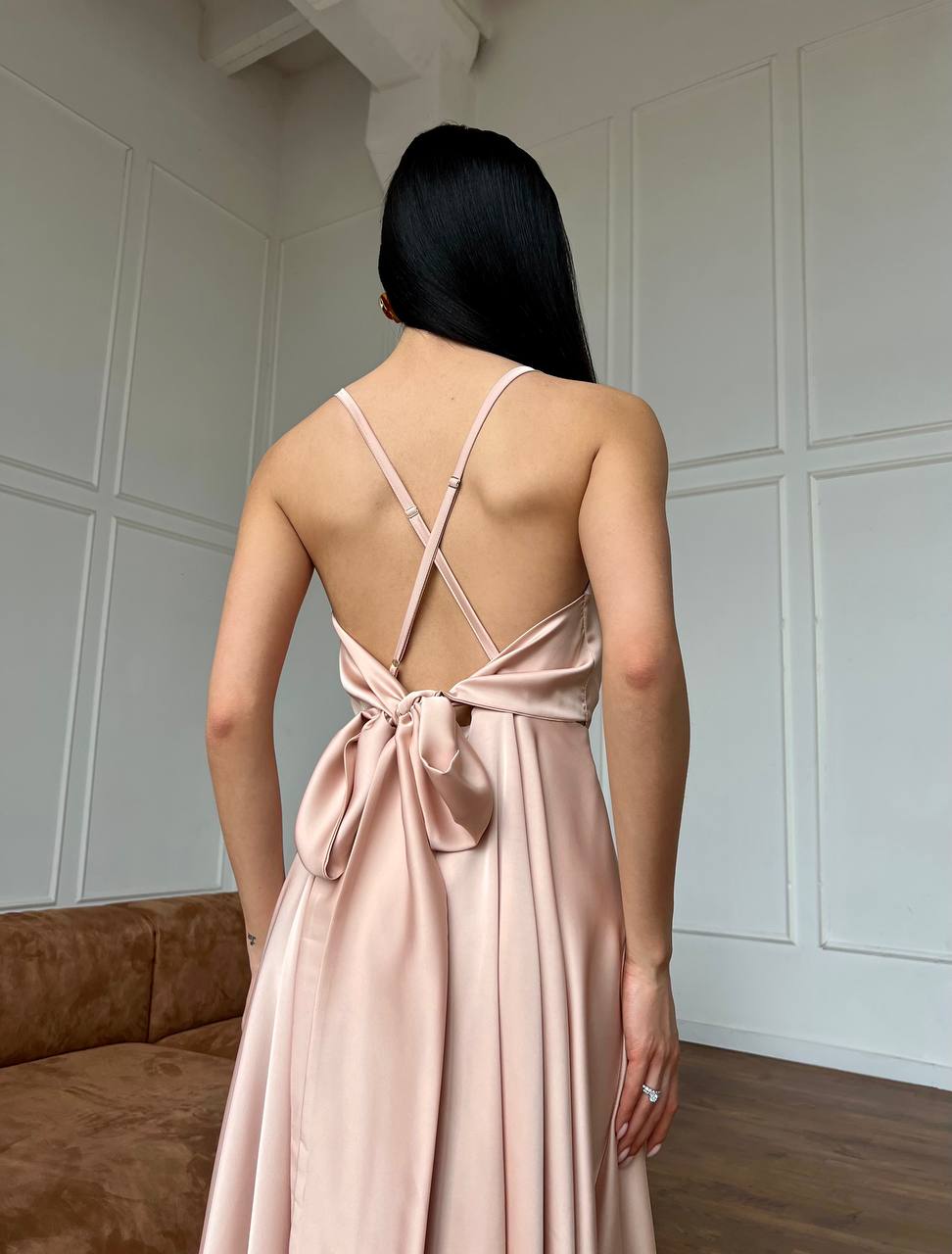 Woman wearing a pink dress with a backless design in a room.