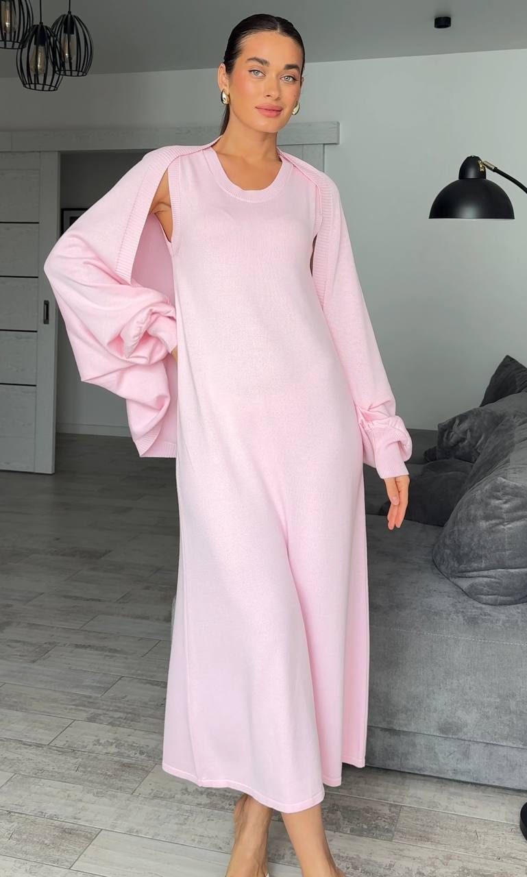 Woman wearing a light pink dress in a room with gray walls and a gray sofa.