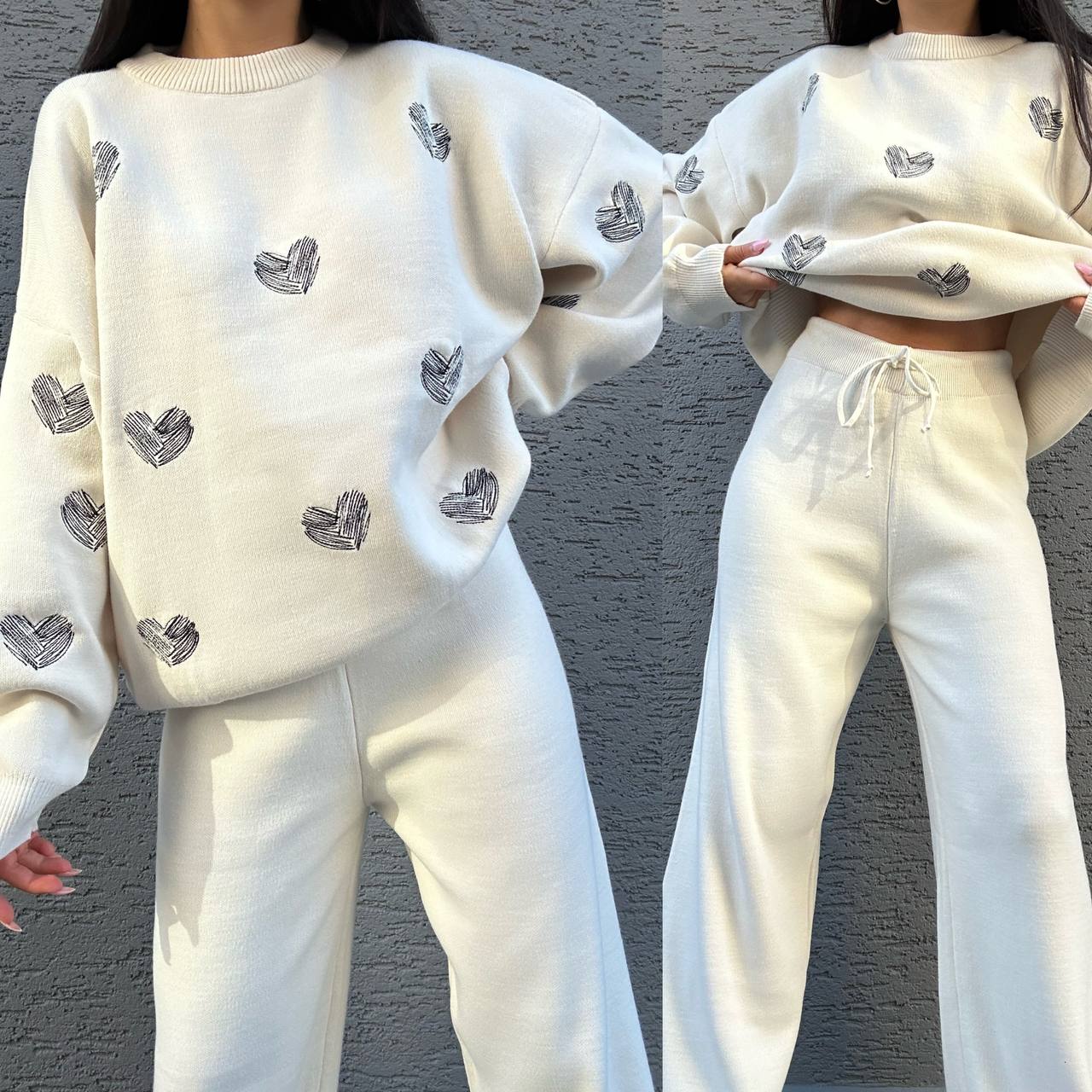 White sweatshirt and pants set with heart patterns worn by a person against a gray background