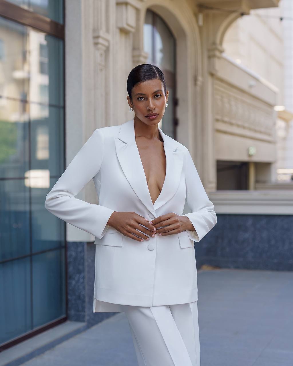 Woman wearing a white suit standing in front of a building