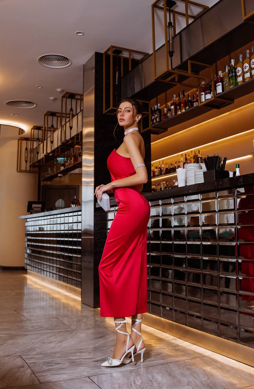 Woman in a red dress standing in a stylish bar setting