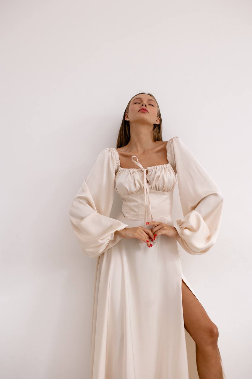 Woman wearing a white dress with a sheer overtop against a plain background