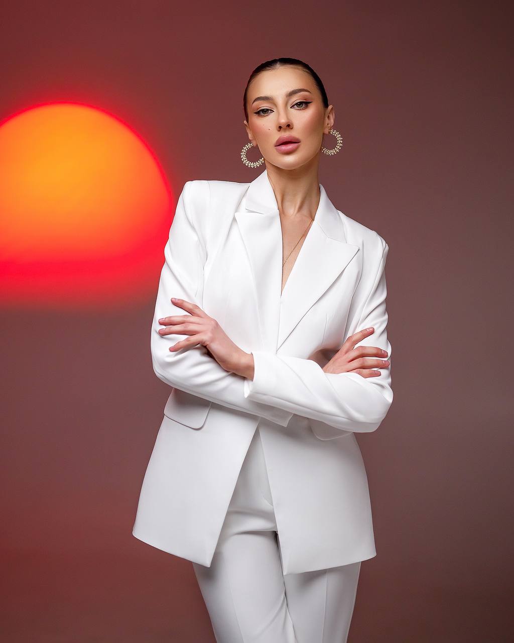 Woman in a white suit standing against a red and orange background