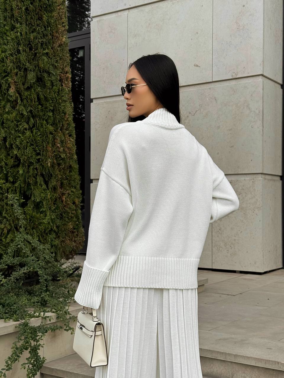 Woman in a white outfit standing outdoors near a building