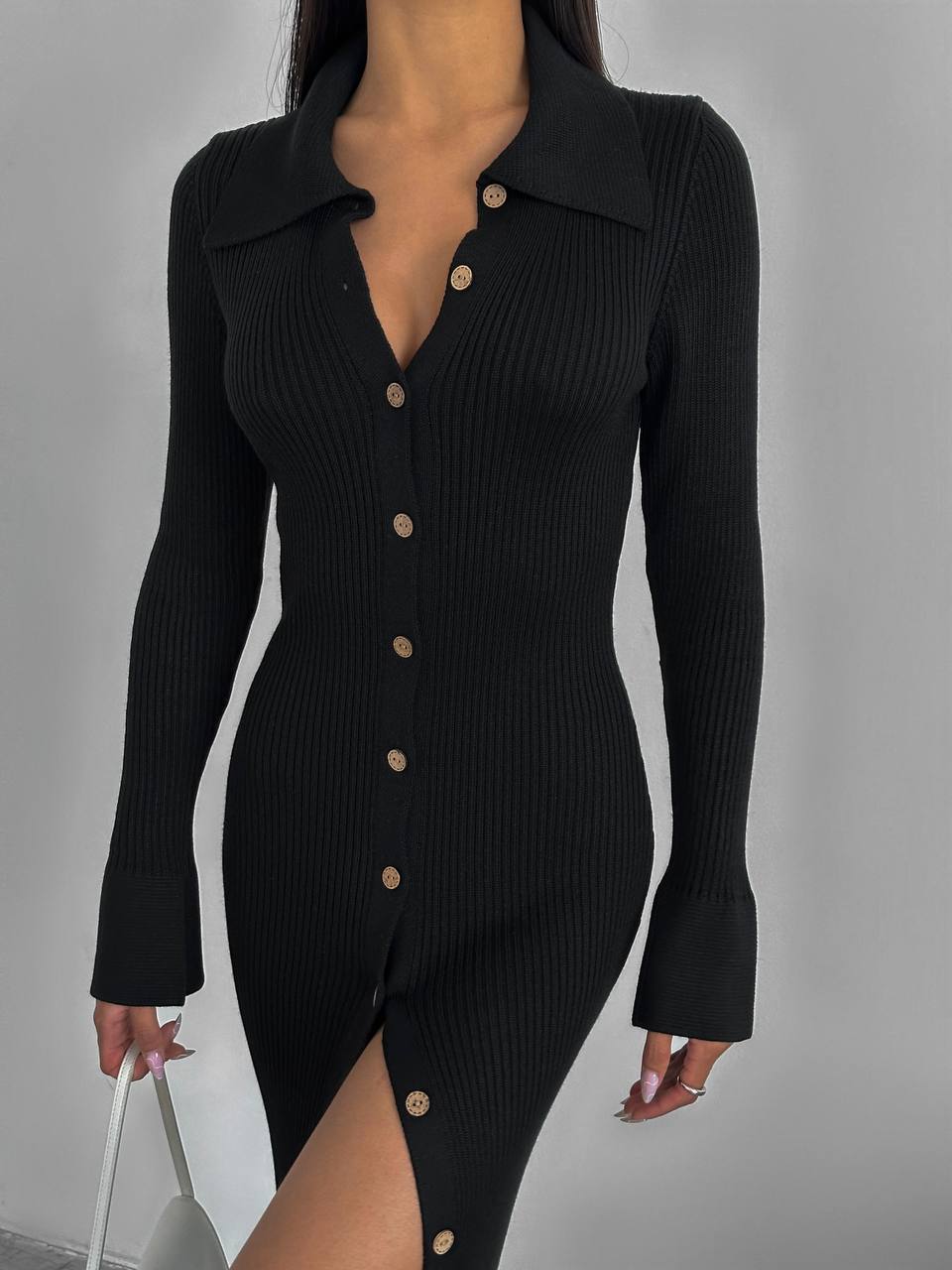 Black ribbed dress with button details on a gray background