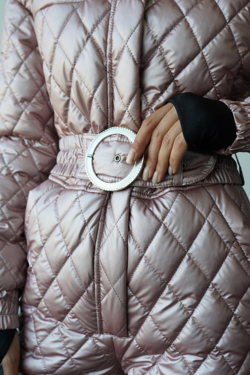 Close-up of a quilted pink jacket with a silver belt buckle.