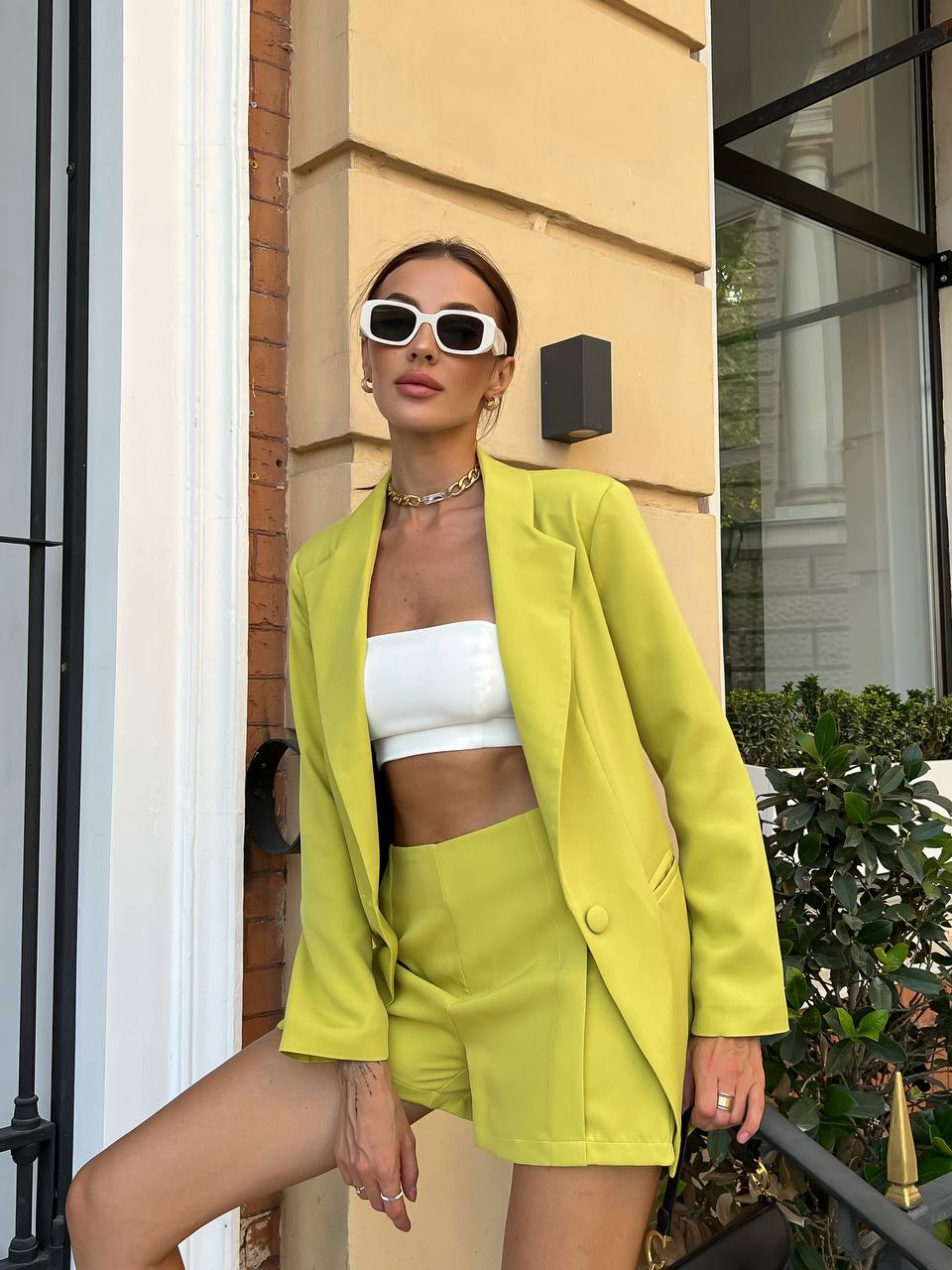 Woman in a bright yellow outfit standing outdoors next to a building.