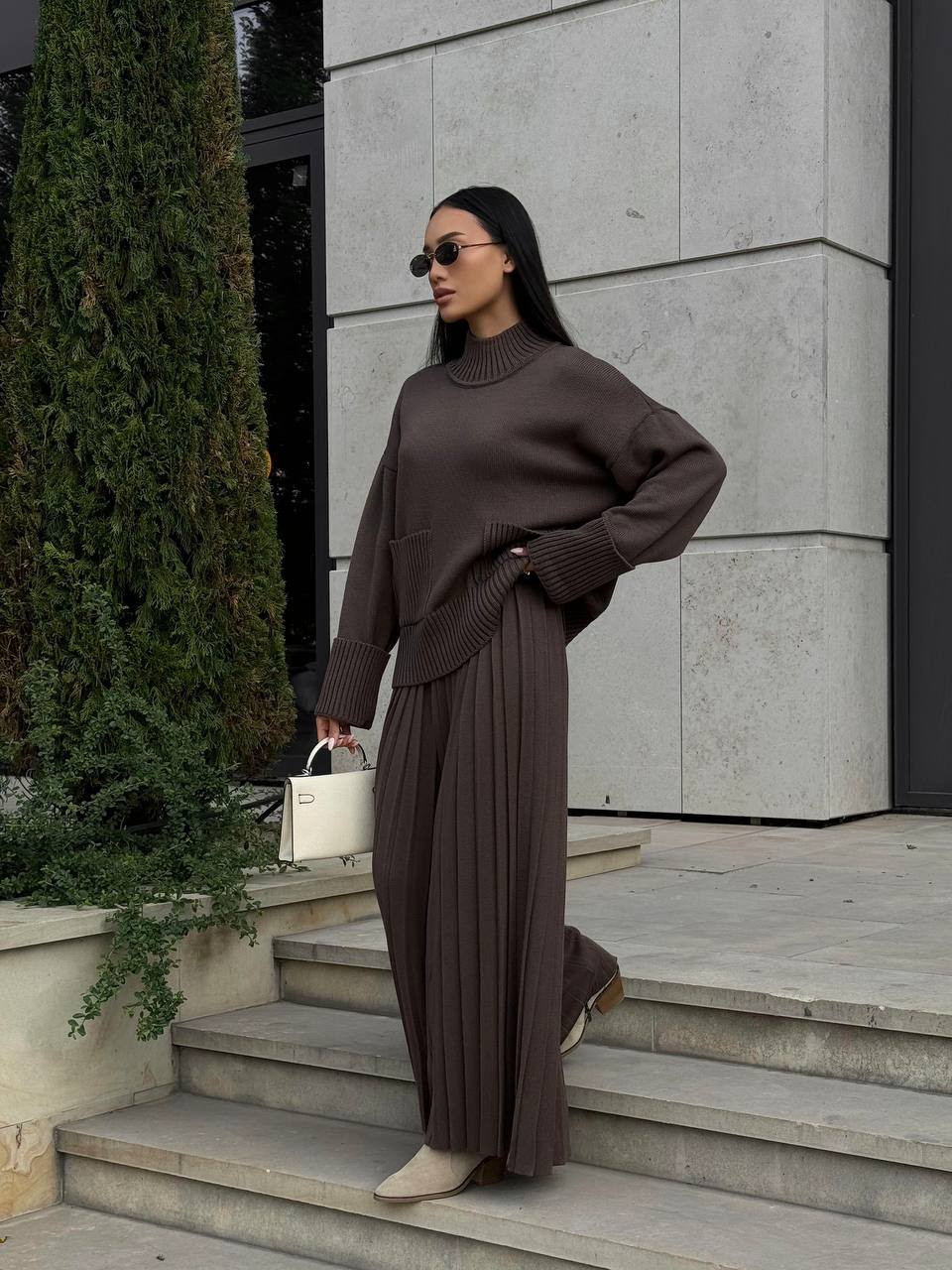Woman in a brown outfit standing on steps outside a building