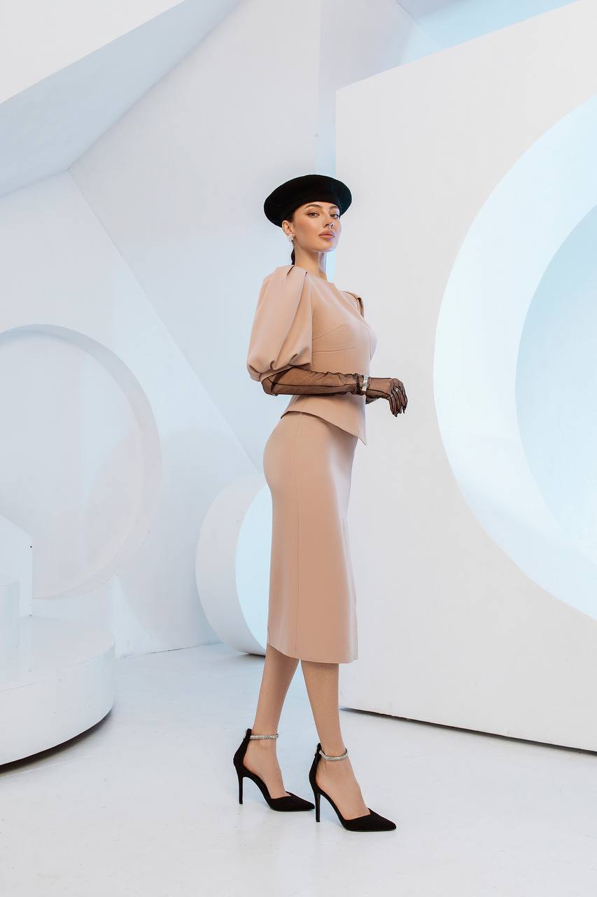 Woman in a beige outfit with a hat standing in a futuristic white room.