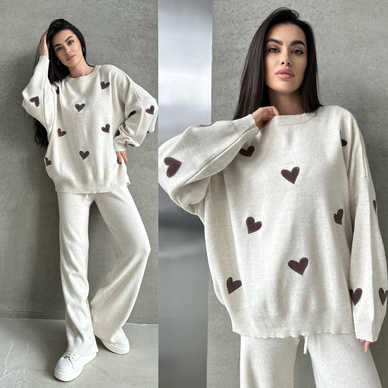 Woman wearing a white sweater with brown heart patterns against a gray background