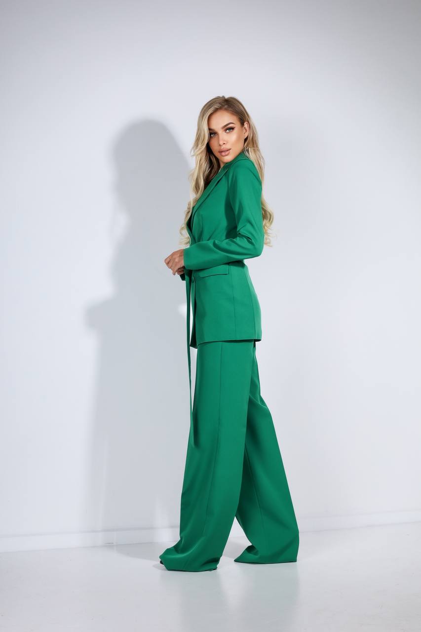 Woman wearing a green suit standing against a white background