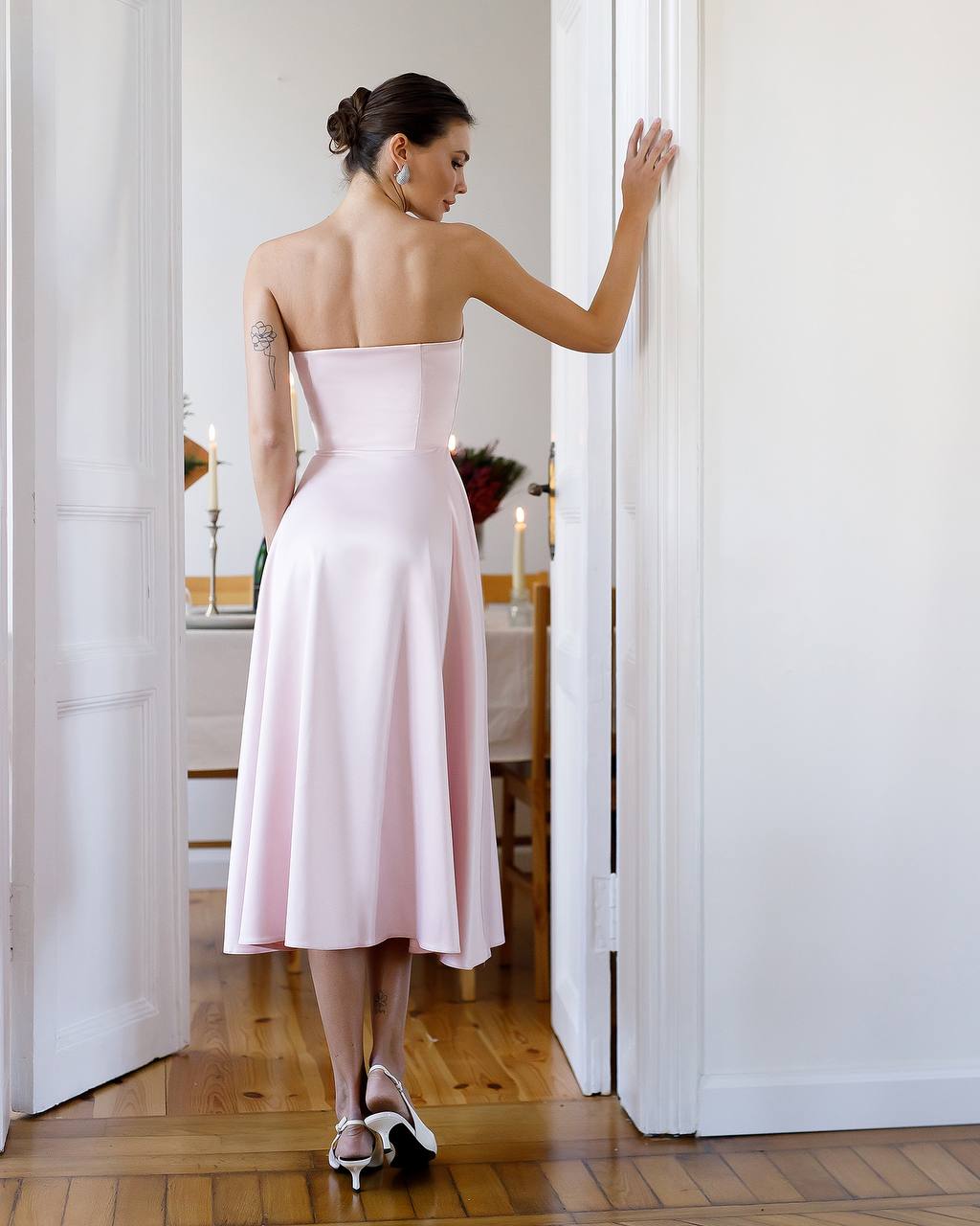 Woman in a pink dress standing in a doorway