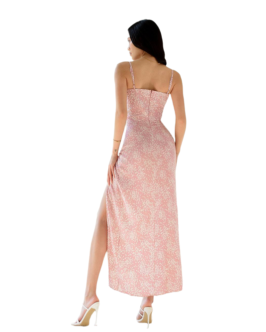 Woman wearing a pink floral dress with a slit on a white background