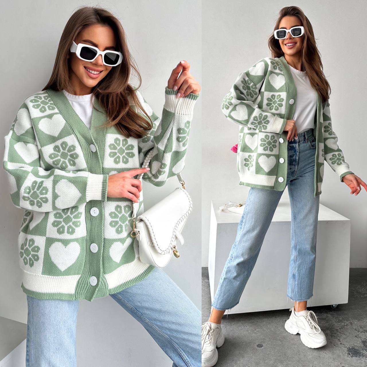 Woman wearing a green and white patterned cardigan with blue jeans indoors.