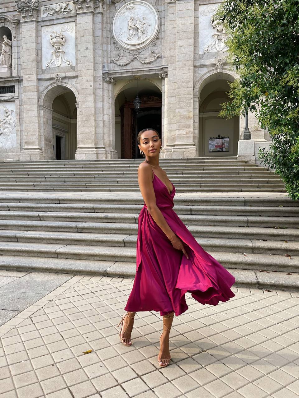 Woman in a pink dress standing on steps in front of an architectural building