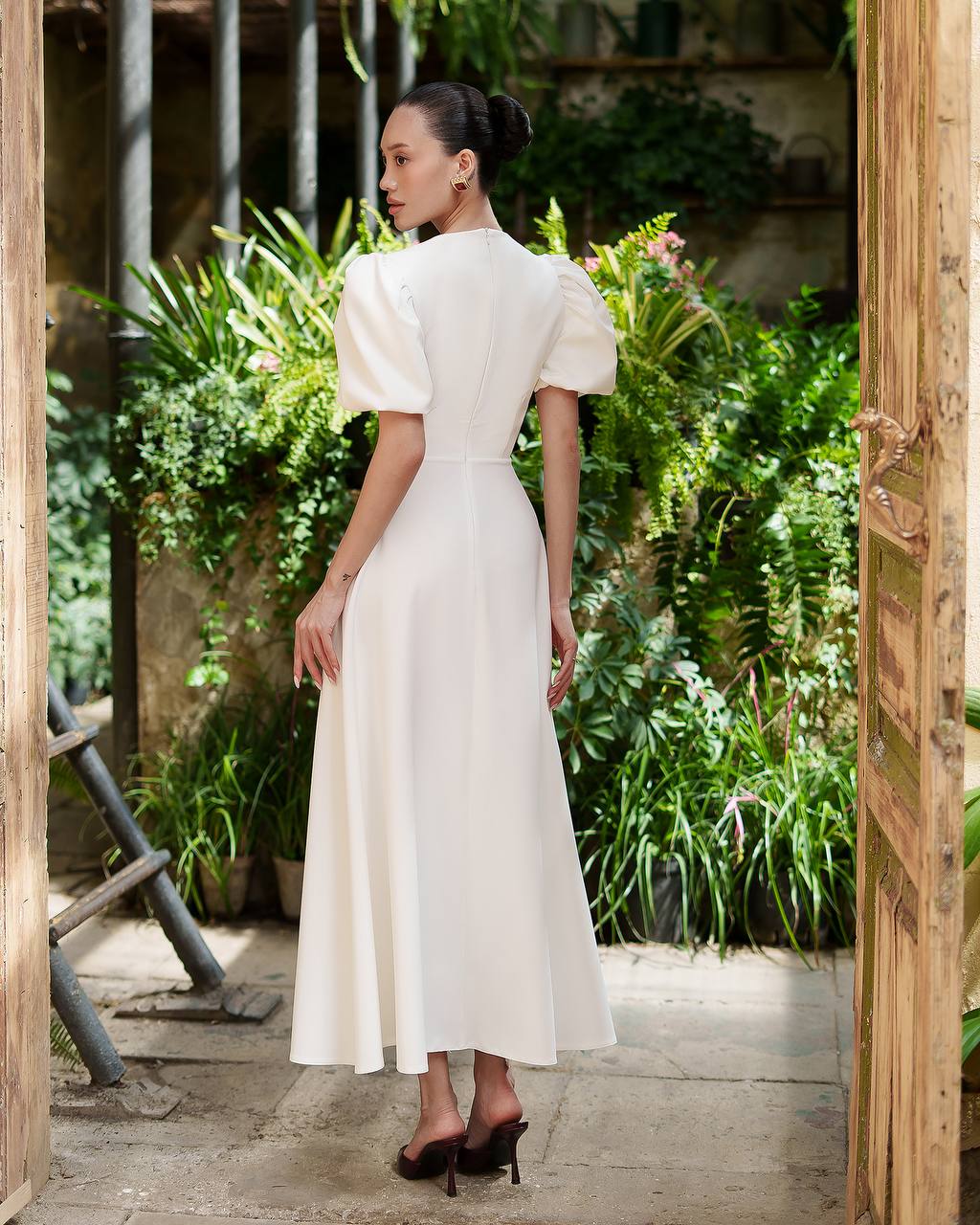 Woman in a white dress standing in a garden setting