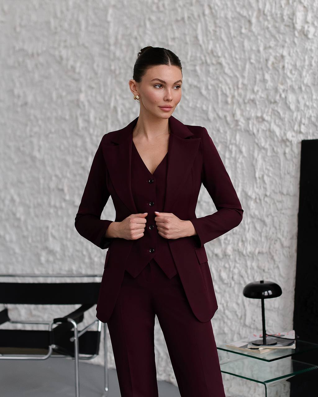 Woman wearing a burgundy suit standing in an office setting.