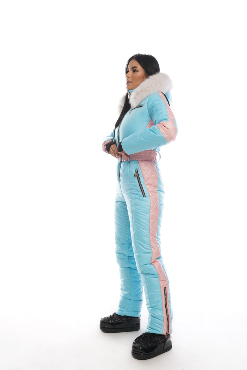 Person wearing a light blue ski suit with pink accents on a white background