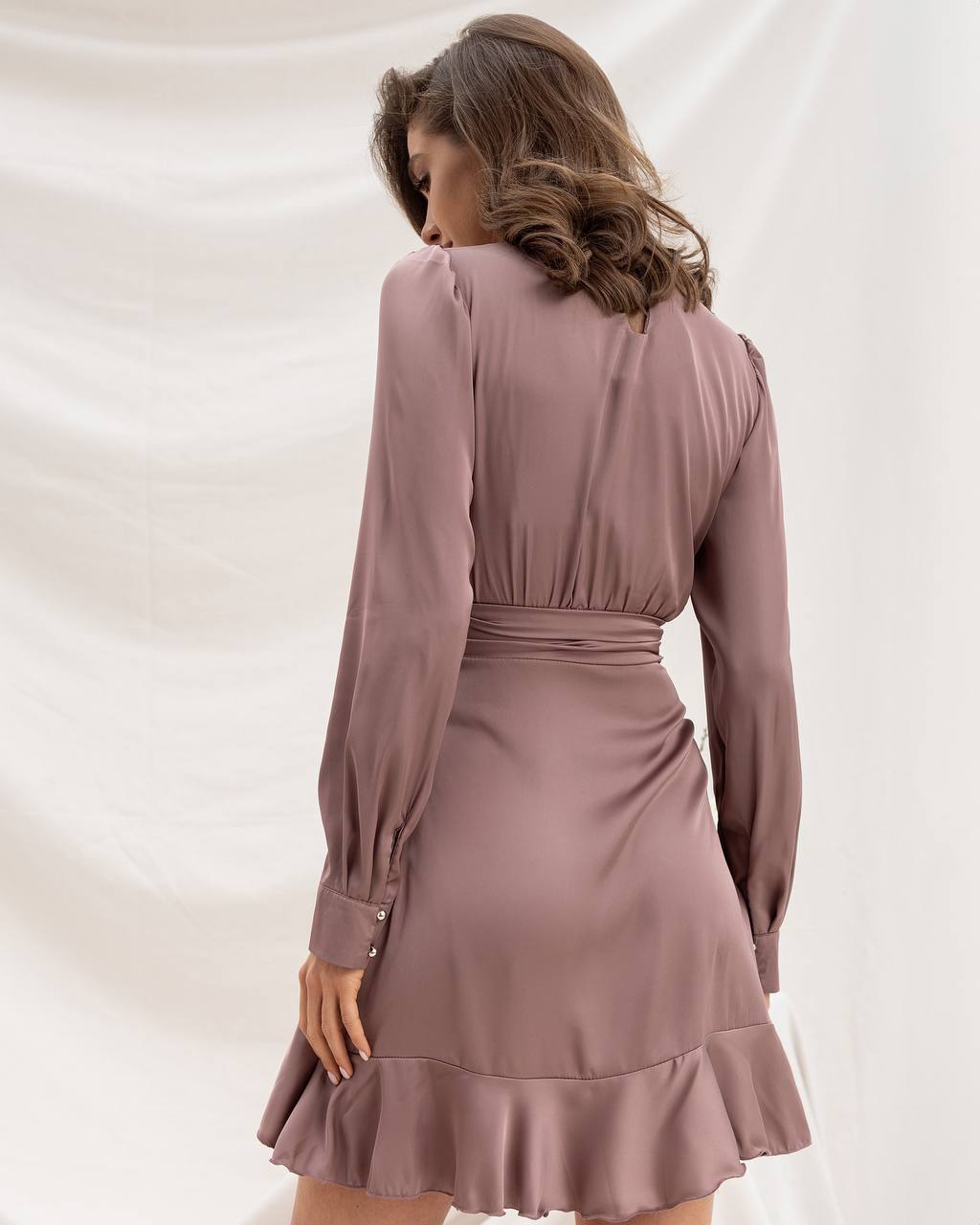 Woman wearing a mauve dress with long sleeves on a white background