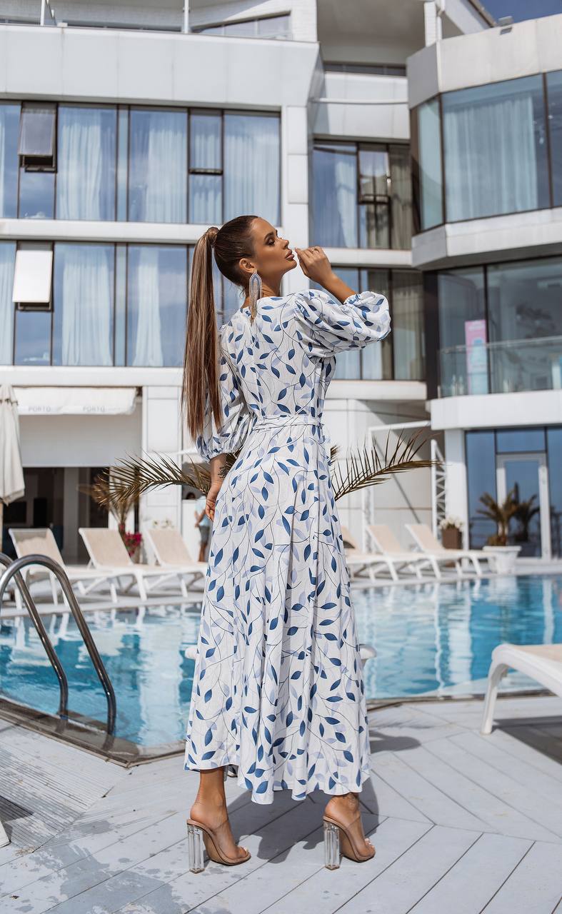 Woman in a patterned dress standing by a pool with modern building in the background