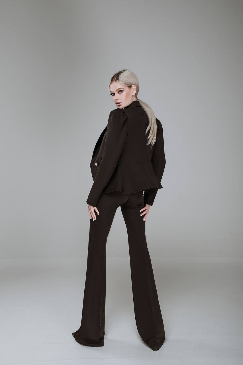 Person wearing a black suit on a plain background