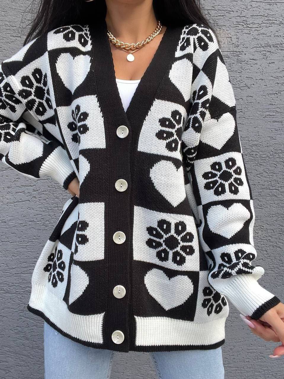 Black and white patterned cardigan worn by a person against a gray background