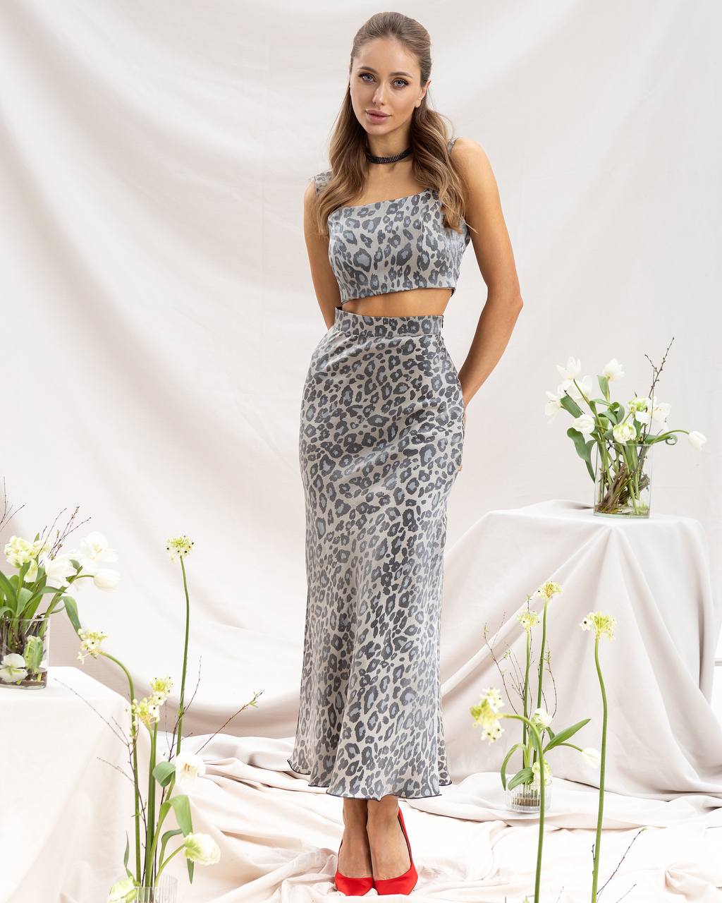 Woman wearing a leopard print outfit with a white background and flowers.