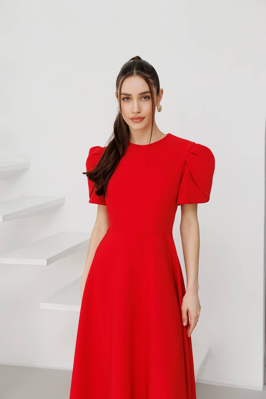 Woman wearing a red dress with puff sleeves against a white background