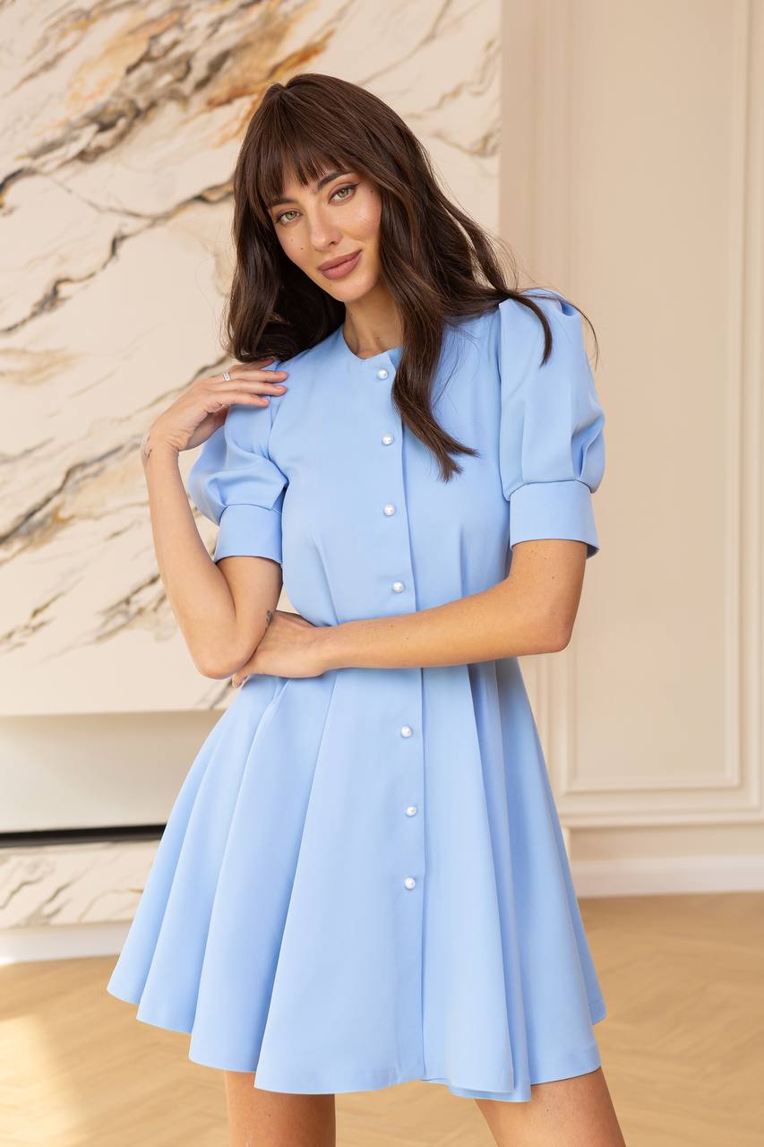 Woman wearing a light blue dress against a marble wall.