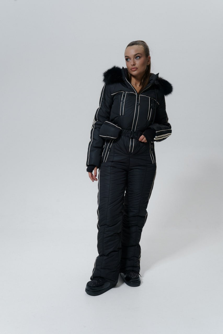 Person wearing a black snowsuit with fur trim on a white background
