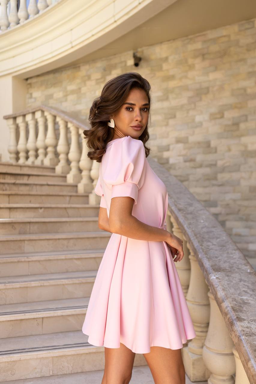 Woman in a pink dress standing on a staircase with a stone wall background