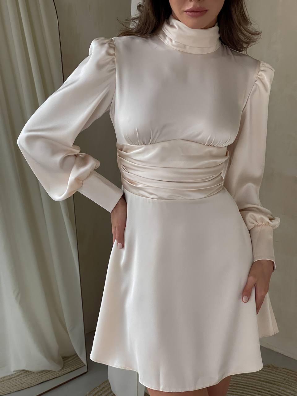 Woman wearing a white dress with long sleeves in a neutral setting