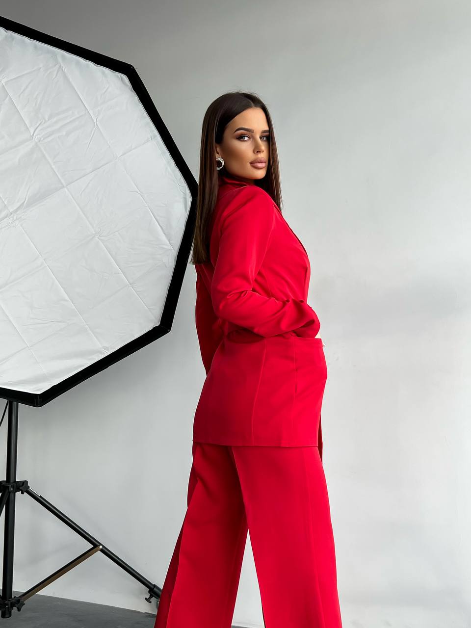Woman in a red outfit standing in front of a photography studio light setup.